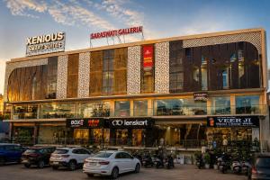 a large building with cars parked in a parking lot at Xenious Smart Suites Greater Noida in Noida