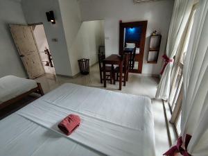 a bedroom with a white bed with a red towel on it at Sithila Villa in Mount Lavinia
