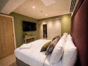 a bedroom with a large white bed with pillows at The Old Malthouse Caerleon in Caerleon