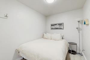 a white bedroom with a bed and a lamp at Mountain View Escape in Big Sky