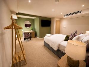 a bedroom with a bed and a desk with a television at The Old Malthouse Caerleon in Caerleon
