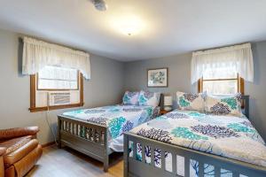 a bedroom with two beds and a chair and windows at Sea Rose in York Beach