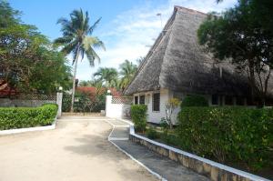 a house with a thatched roof and a palm tree at Glory Ocean Villas - Diani in Diani Beach