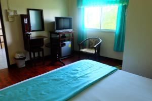 a bedroom with a bed and a desk and a television at J-Safe Guesthouse in Sukhothai