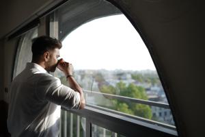 a man talking on a cell phone looking out of a window at FLH Residences, Ambawadi in Ahmedabad