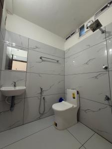 a white bathroom with a toilet and a sink at IB homes in Changanācheri