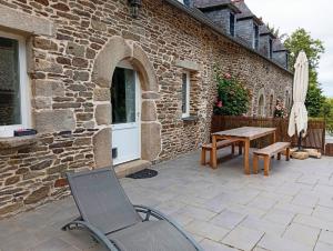 a patio with a table and a chair and an umbrella at Bienvenue à Longère Bihan - Chambres d'Hôtes - Bed & Breakfast in Plévin