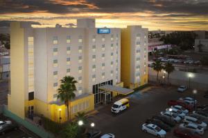 a large building with cars parked in a parking lot at City Express by Marriott Mexicali in Mexicali