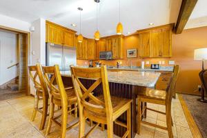 a kitchen with wooden cabinets and a island with chairs at Timber Ridge 4 in Teton Village