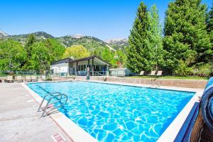 a swimming pool with a house and mountains in the background at Timber Ridge 4 in Teton Village