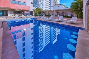 a swimming pool with lounge chairs and a building at City Express Plus by Marriott Puerto Vallarta in Puerto Vallarta
