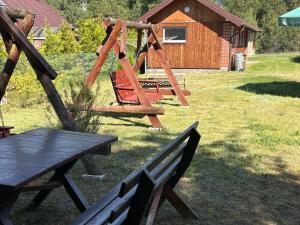 a playground with a bench and a wooden swing at "Rowerowa Przystań" turystyka wiejska & agroturystyka nad jeziorem Serwy w sercu Puszczy in Sucha Rzeczka