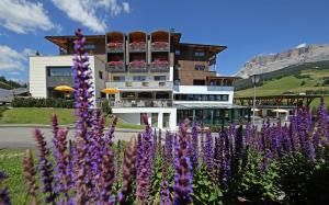 a building with purple flowers in front of it at Hotel Ciasa Soleil in La Villa