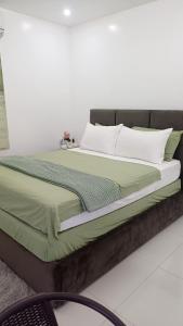 a large bed with green and white sheets and pillows at Cai Residence - Stylish 2BR Staycation near EK & Tagaytay Gateway in Santa Rosa