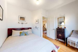 a white bedroom with a bed and a dresser in it at Old Town Cottage in Steamboat Springs