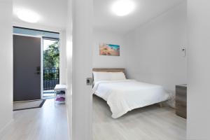 a white bedroom with a bed and a sliding glass door at Saratoga Beach Villa 4 in Oyster Bay