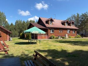 a large brick house with a green tent in front of it at "Rowerowa Przystań" turystyka wiejska & agroturystyka nad jeziorem Serwy w sercu Puszczy in Sucha Rzeczka