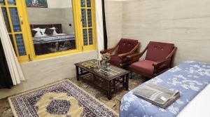 a room with a bed and two chairs and a table at The Oasis inn in Karnaprayāg