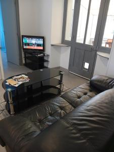 a living room with a leather couch and a television at Tour de bridier in La Souterraine