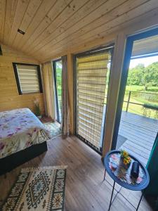 a bedroom with a bed and a table and a balcony at Căsuța din pădure KSIM in Curtea de Argeş