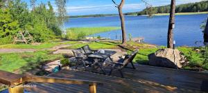 a wooden deck with a table and chairs and a lake at Suvikoti in Lokalahti