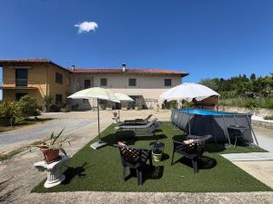 a yard with tables and chairs and umbrellas at Bed & Breakfast Cascina Beatrice in Rodello