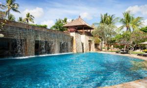 - une piscine avec une cascade en face d'une maison dans l'établissement AYANA Resort Bali, à Jimbaran