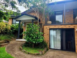 a brick house with a tree in front of it at Pandanus Studio Lennox Head in Lennox Head
