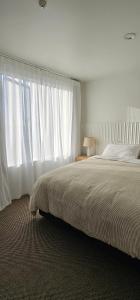 a bedroom with a large bed with white curtains at Waves Kaikoura Waterfront Apartment #1 in Kaikoura