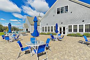 a patio with blue chairs and tables and umbrellas at Little Spruce Cottage in Arundel