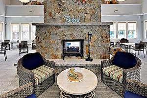 a lobby with a stone fireplace with two chairs and a table at Little Spruce Cottage in Arundel