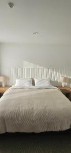 a bedroom with a large white bed with two tables at Waves Kaikoura Waterfront Apartment #1 in Kaikoura
