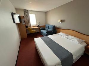 a hotel room with a bed and a chair at Brit Hotel Confort Montauban in Montauban