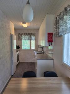 a kitchen with white cabinets and a table and chairs at Home nest in Seinäjoki