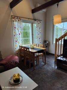 a living room with a table and chairs and a tv at Holisko in Ylläsjärvi