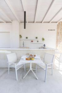 a white kitchen with a table and two chairs at NC Boutique B&B in Torre San Giovanni Ugento