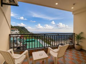 a balcony with chairs and a table and a view at The Moksh DA Hotel A Premium Property Near Jaypee Hotel in Mussoorie