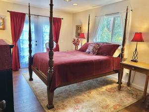 a bedroom with a canopy bed with red sheets and windows at Bigfork Lake Getaway in Bigfork