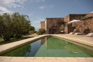 a swimming pool in a yard with chairs and a building at Il Mulino di Scauri in Pantelleria