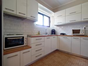 a white kitchen with white cabinets and a microwave at Rose Garden in Melíkia +16 photos
