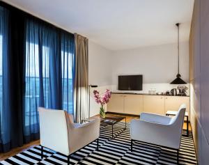 ein Wohnzimmer mit 2 weißen Stühlen und eine Küche in der Unterkunft Sense Hotel Sofia, a Member of Design Hotels in Sofia