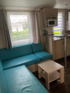 a living room with a blue couch and a table at Omaha beach mobilhome in Colleville-sur-Mer