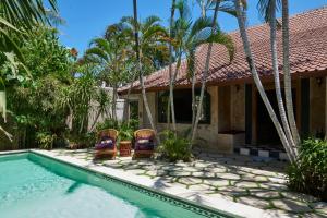 a house with two chairs and a swimming pool at The Island Houses Seminyak in Seminyak