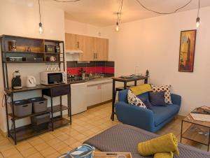 a living room with a blue couch and a kitchen at L'Aiglon Studio cocon au coeur de Gap in Gap