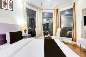 a white bed in a room with large windows at Townhouse by OYO Brahma Sarovar Formerly Krishna mahal in Kurukshetra