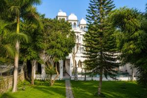 a large white building with trees in front of it at YAMA Villa Udaipur in Udaipur