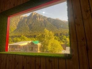 a window with a view of a house and a mountain at Crown royal shahjee stay in Rezan