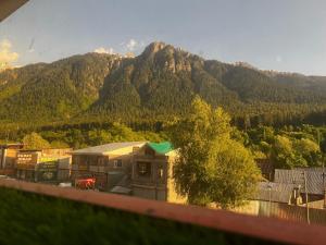 a view of a mountain with a house and trees at Crown royal shahjee stay in Rezan