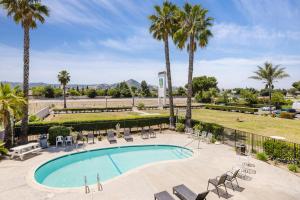 a swimming pool with chairs and palm trees at SureStay by Best Western Morgan Hill in Morgan Hill