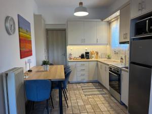 a kitchen with white cabinets and a table and blue chairs at Eleni village House in Kamena Vourla
